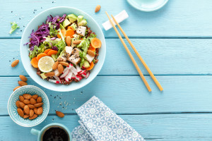 Bowl with grilled chicken meat, brown rice and fresh vegetable salad of avocado, radish, cabbage kale, carrot, and lettuce leaves. Healthy and delicious dietary lunch. Top view