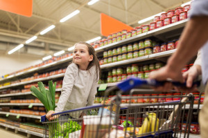 child with father buying food at grocery store